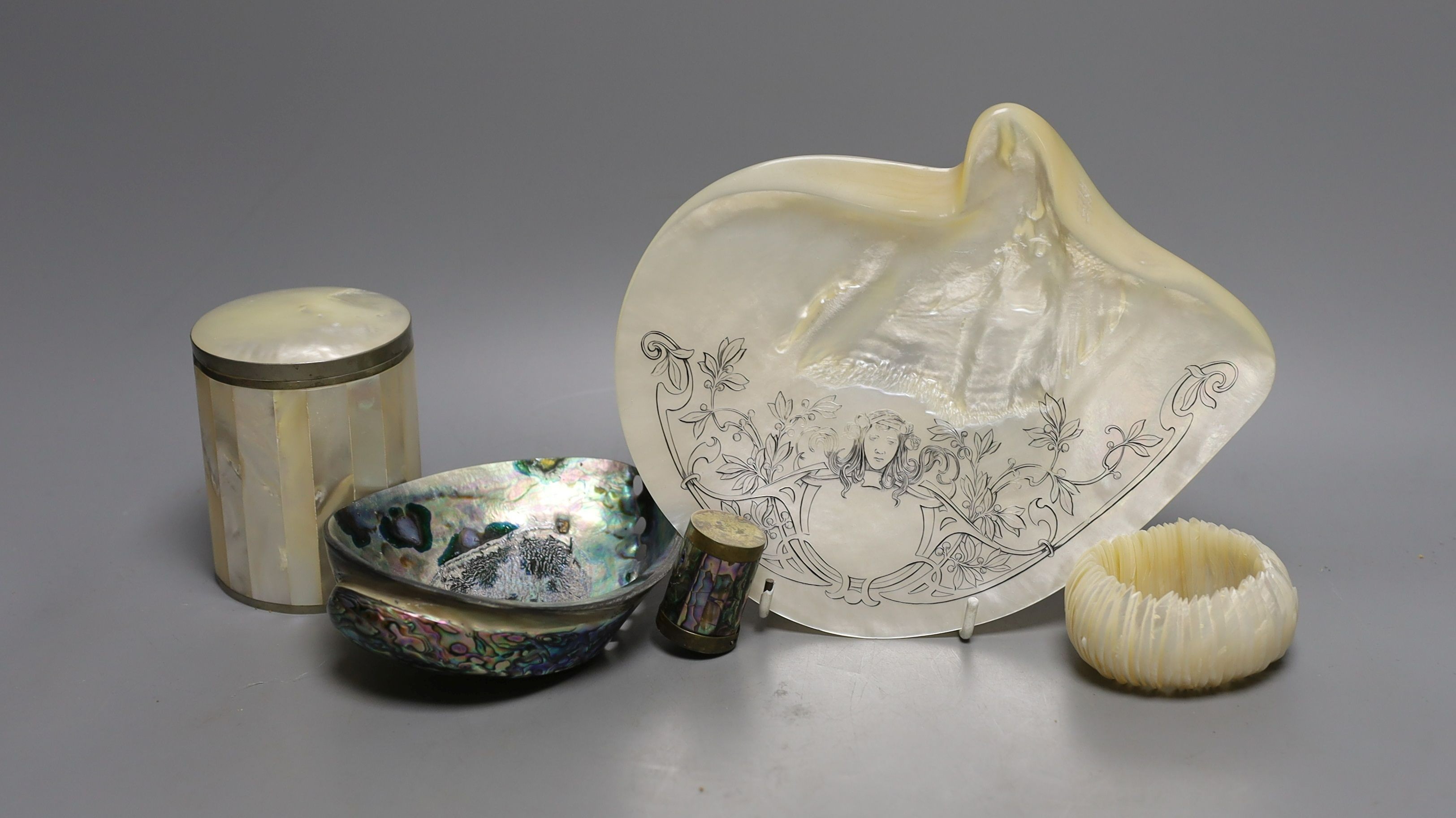 An engraved pearl shell, 22cm, a cylindrical box and bracelet, and two abalone shells